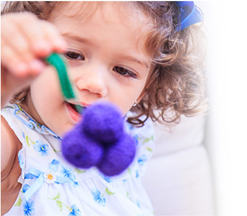 Menina segurando uvinha de crochet