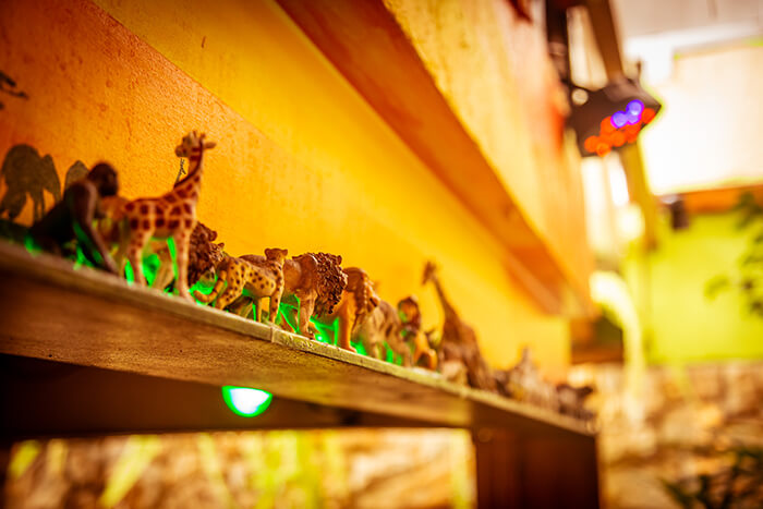 Foto do detalhes da decoração do espaço: mini animais caminham no horizonte sobre a mesa do bolo.