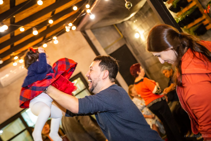 foto de festa : tio brincando de jogar a bebê no alto e sorrindo. 